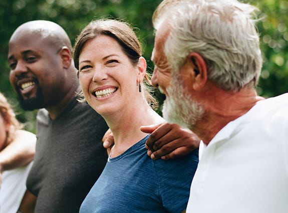 A group of people lined up together with arms around shoulders, smiling