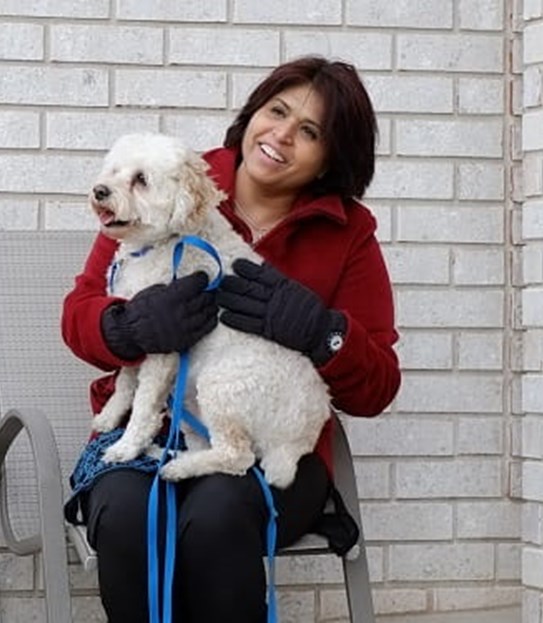 Sharon Sandhawalia holding a dog and smiling