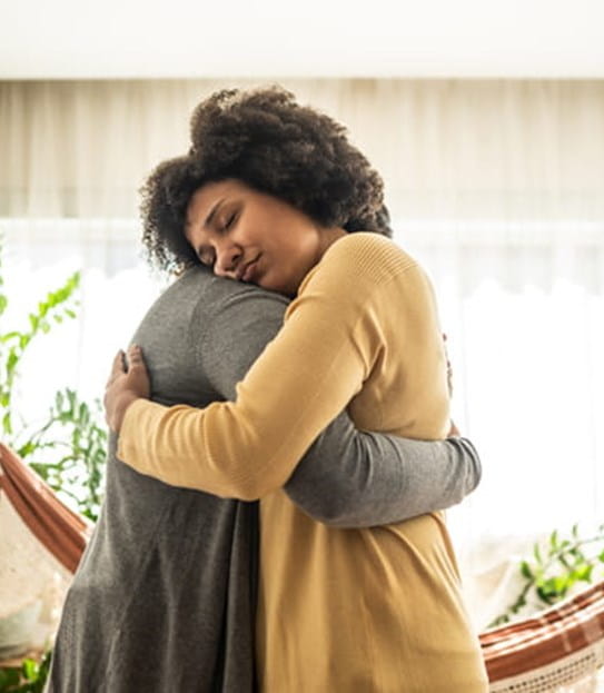 Deux personnes s'embrassant dans une pièce lumineuse décorée de plantes