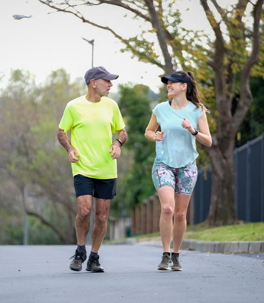 Une femme et un homme souriants courent à l’extérieur