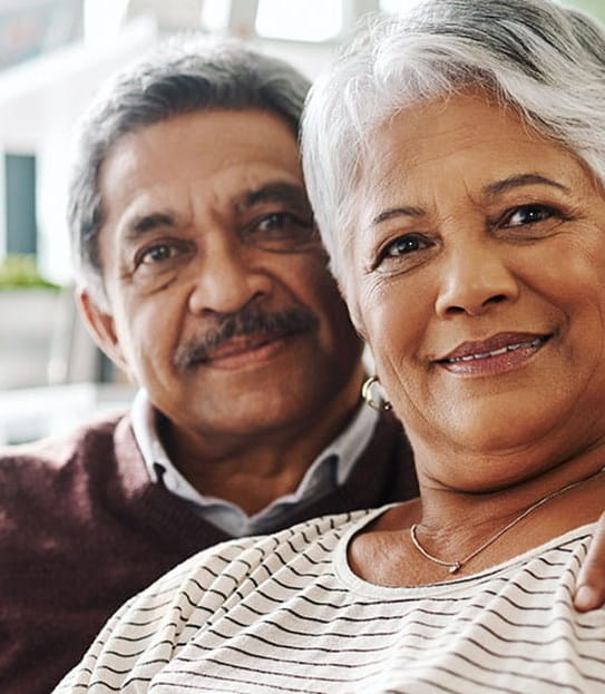 A person has their arm around their partner and they are both seated on a couch.