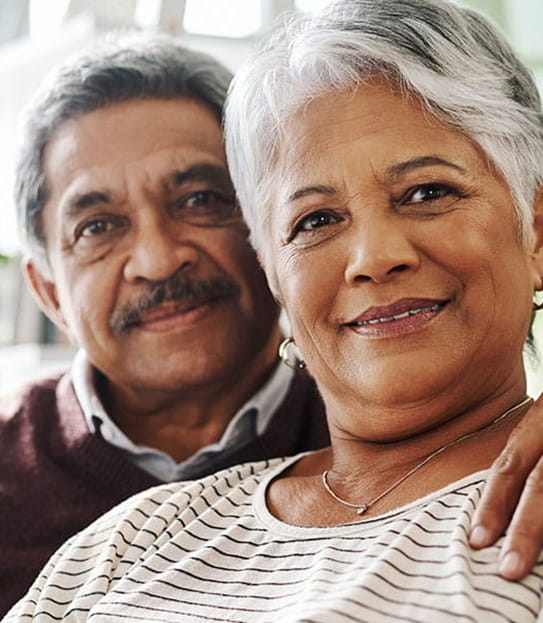 Une personne a le bras autour de sa partenaire, et ils sont tous les deux assis sur un canapé.