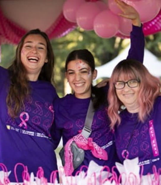 3 volunteers smiling with their arms up, wearing Canadian Cancer Society CIBC Run for the Cure shirts