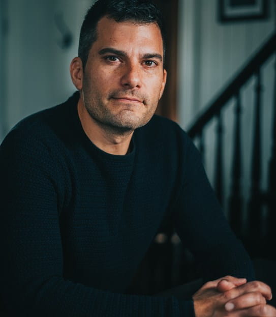 A portrait of Craig Savill with his hands together looking at the camera.