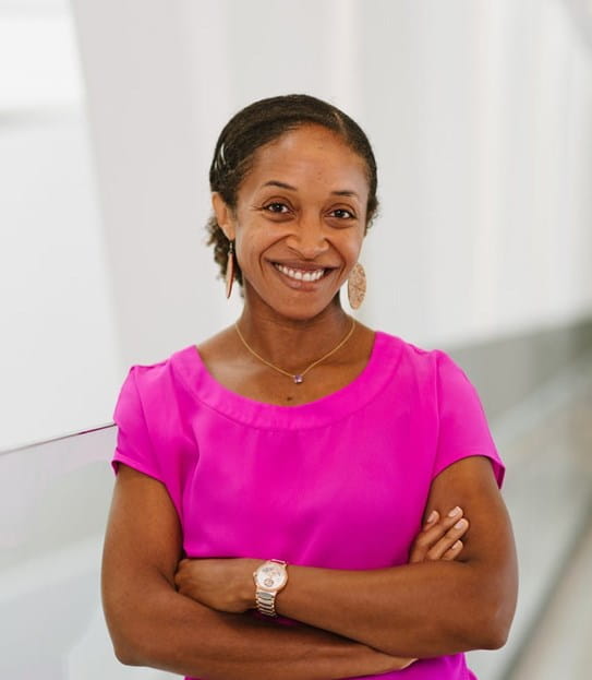 Dr Aisha Lofters smiling with her arms crossed.