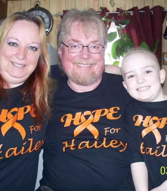 (From left to right): Juanita, Leonard and Hailey Rodenhiser smiling at the camera wearing shirts that say 'Hope for Hailey'