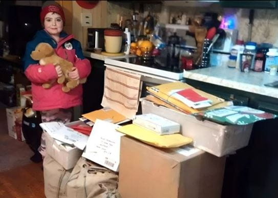 Hailey holding a toy dog and standing next to boxes of Christmas cards.