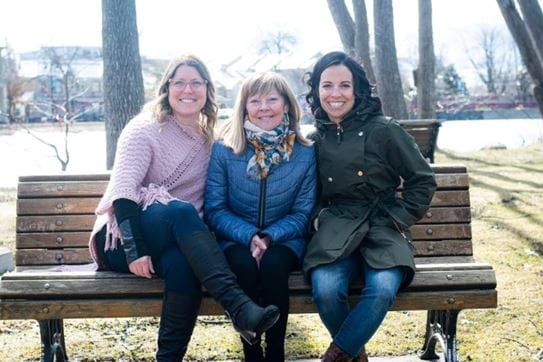 Louise-Hélène is sitting on a bench with her two daughters.