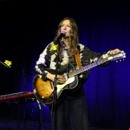 BEYRIES debout avec sa guitare une scène décorée de jonquilles