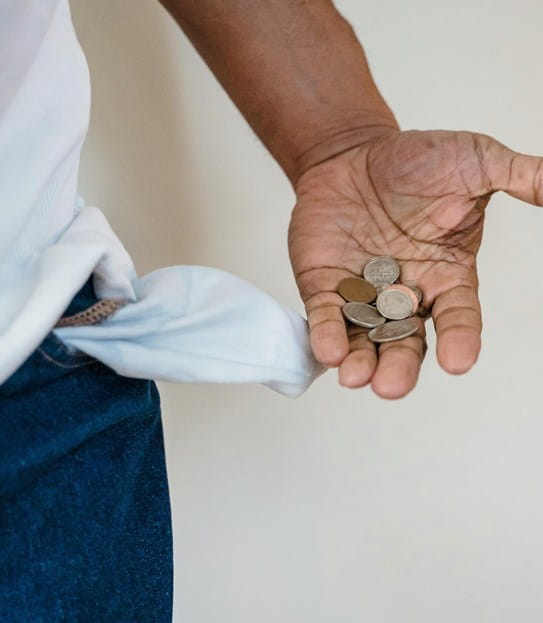 A person’s pants pocket turned inside out and their hand holding coins.