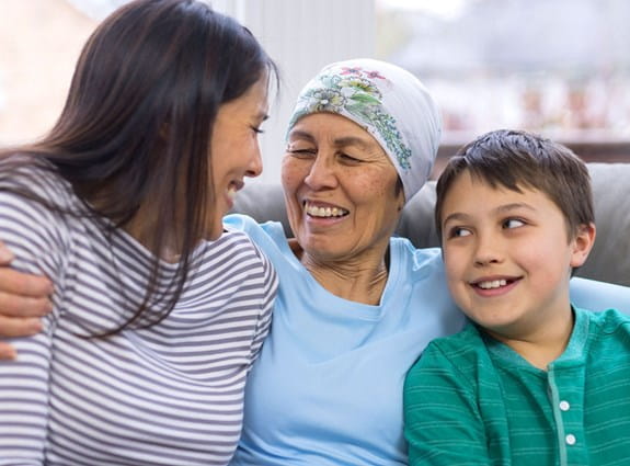A photo of a mom sitting on a sofa with her daughter and young son.