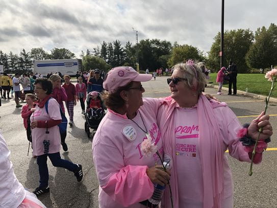 Wendy Garner et une autre participante de la Course à la vie CIBC, vêtues de rose et tenant une fleur.