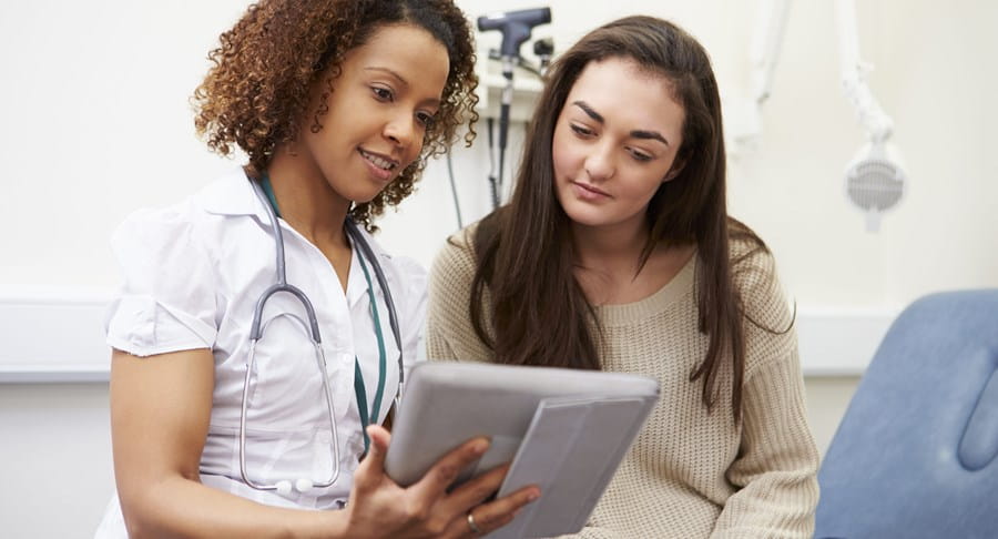 Une patiente et une professionnelle de la santé en train de regarder quelque chose sur une tablette