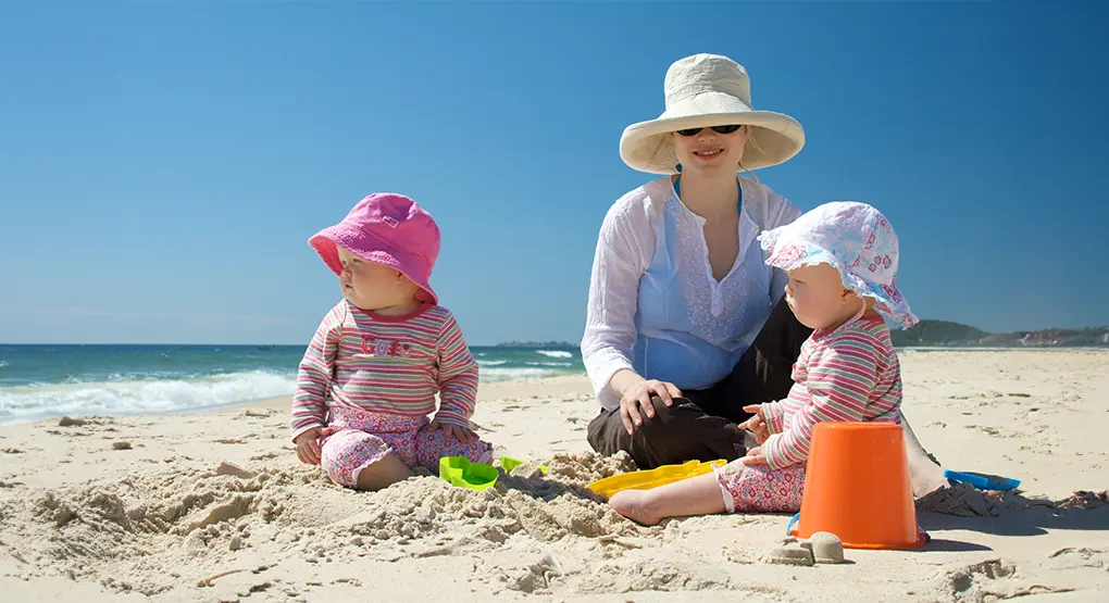 Un parent avec deux bébés sur une plage
