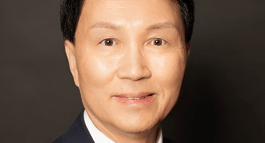 Bammy wong Bammy Wong smiling. He wears a dark coloured suit, white shirt and red tie.