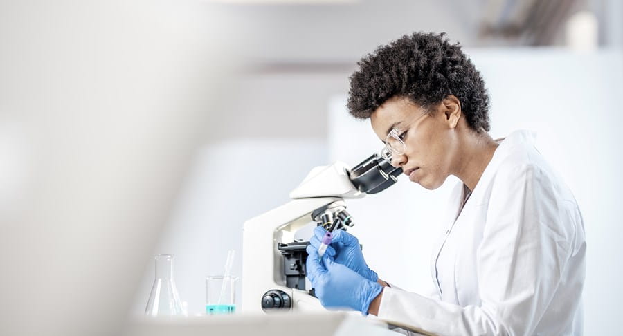 Une chercheuse regardant dans un microscope.