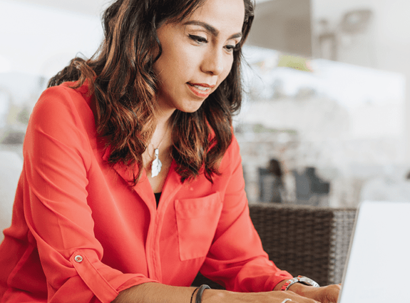 A woman sits on a couch working on her laptop