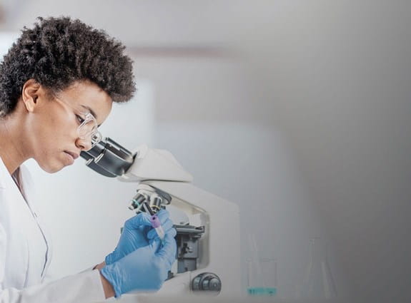 Une femme regarde dans un microscope.